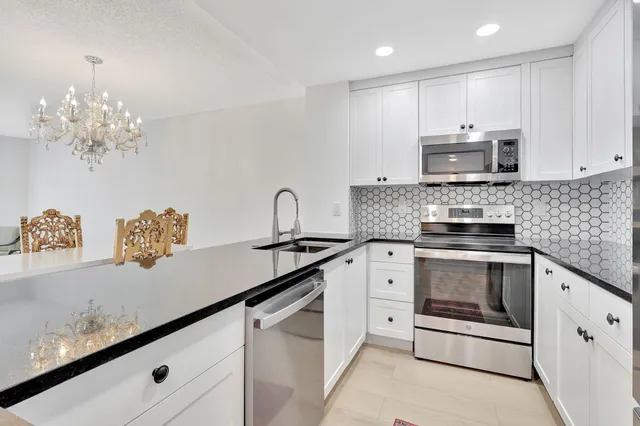 a kitchen with granite countertop white cabinets white stainless steel appliances with a sink and dishwasher