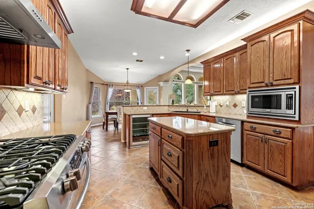 a kitchen with stainless steel appliances granite countertop a stove a sink and a microwave