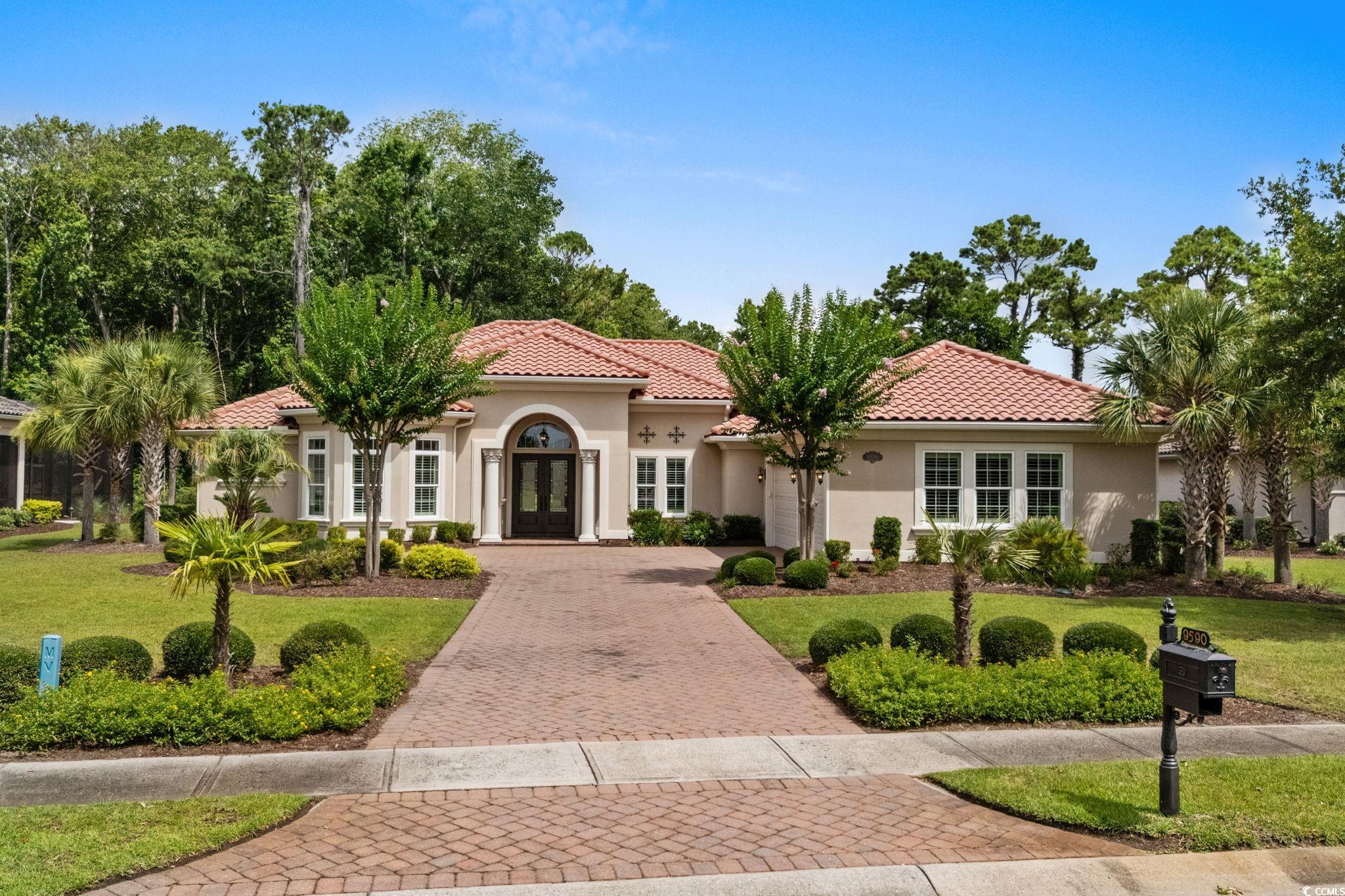 Mediterranean / spanish-style house featuring a front lawn, decorative driveway, stucco siding, a tiled roof, and an attached garage