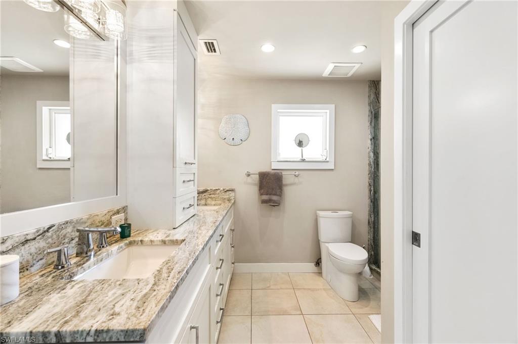 2140 Shad Court Naples, FL 34102 - Photo 41 of 44 a bathroom with a granite countertop double vanity sink a mirror and a toilet