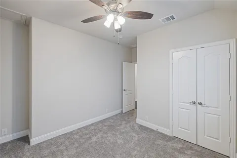 a view of an empty room and chandelier fan