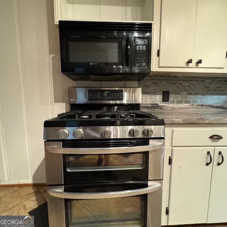 an empty room with wooden floor chandeliers and hallway