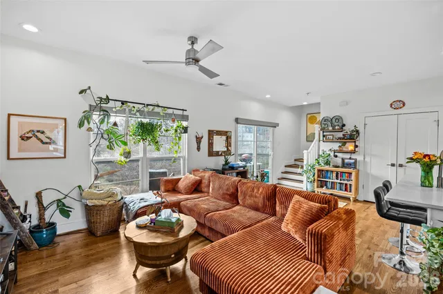 a living room with furniture a dining table with wooden floor and potted plants