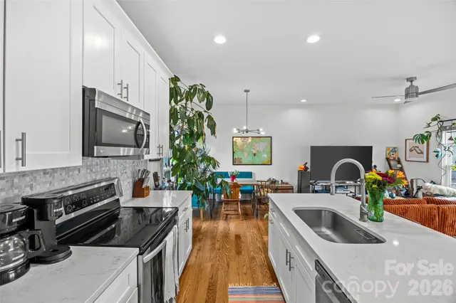 a living room with stainless steel appliances furniture and a flat screen tv