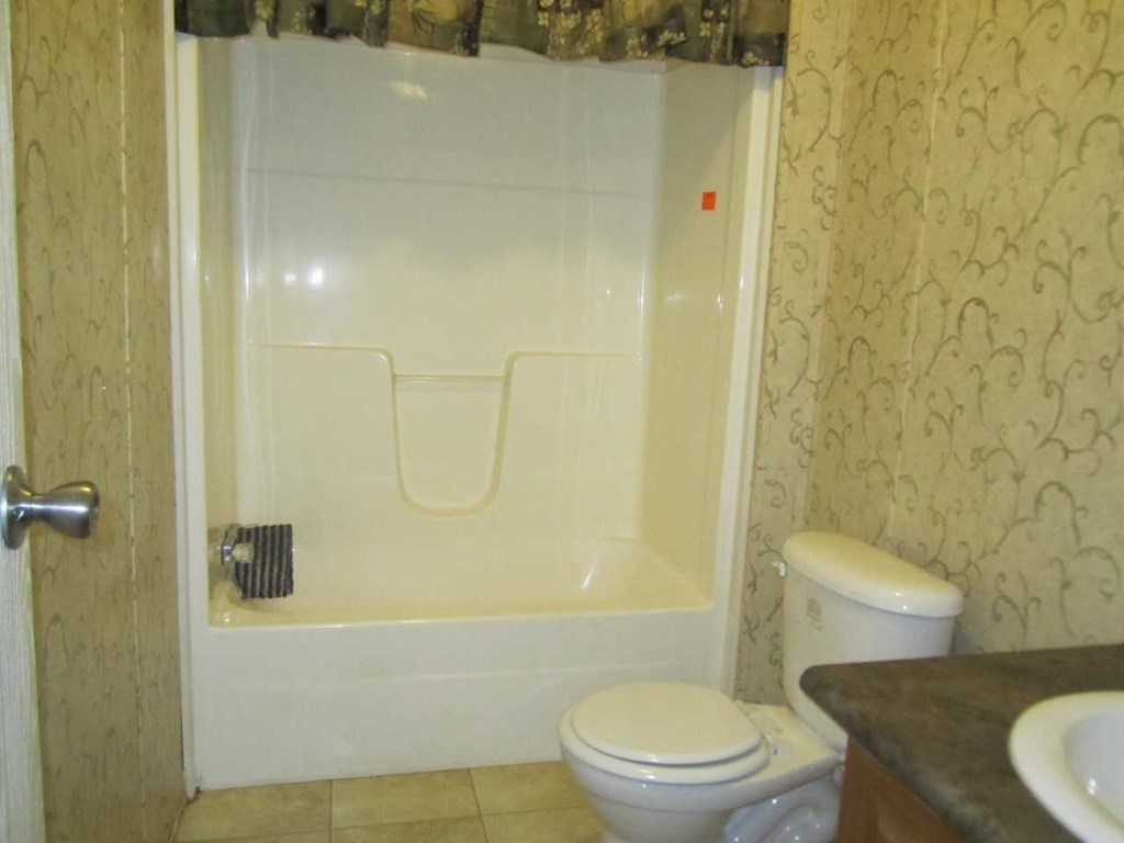 148 5th Road, Unit 20 Haddock, GA 31033 - Photo 8 of 12 a white toilet sitting next to a bathroom sink and a shower
