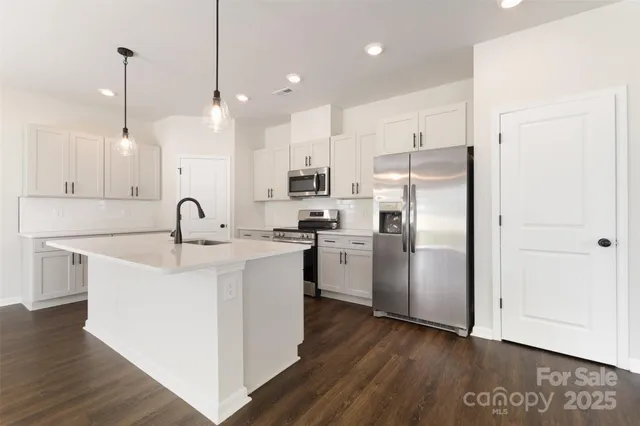 a kitchen with kitchen island white cabinets stainless steel appliances and wooden floor