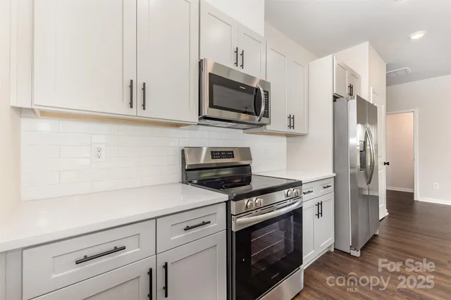 a kitchen with stainless steel appliances white cabinets and a stove top oven