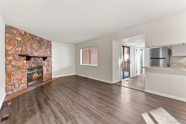 an empty room with wooden floor fireplace and windows