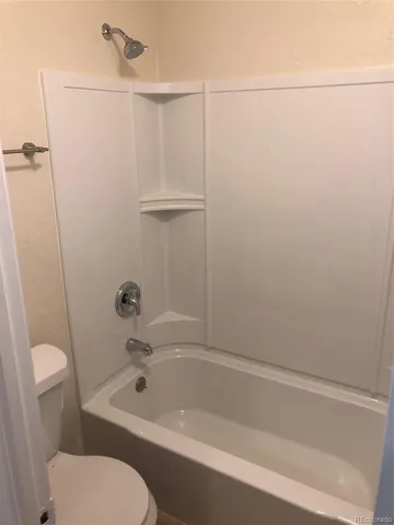 a white toilet sitting next to a bath tub