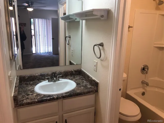 a bathroom with a granite countertop sink toilet and shower