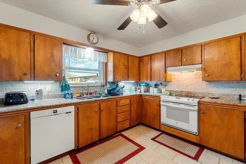 a kitchen with stainless steel appliances granite countertop a sink a stove cabinets counter space and a window