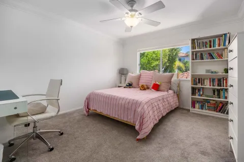 a bedroom with a bed a book shelf and a window