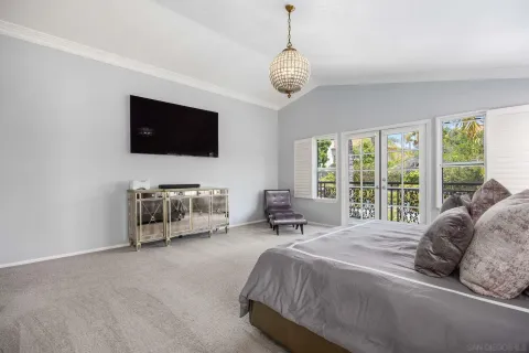 a spacious bedroom with a bed and a flat tv screen on dresser