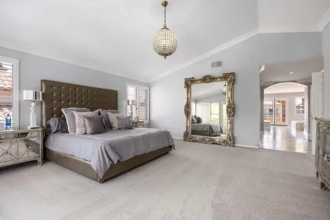 a spacious bedroom with a bed mirror and window