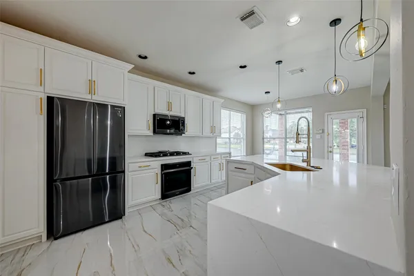 a kitchen with stainless steel appliances granite countertop a refrigerator a stove a sink and a refrigerator