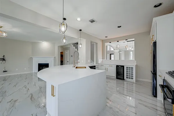 a large white kitchen with a stove a sink dishwasher a refrigerator and a fireplace with wooden floor