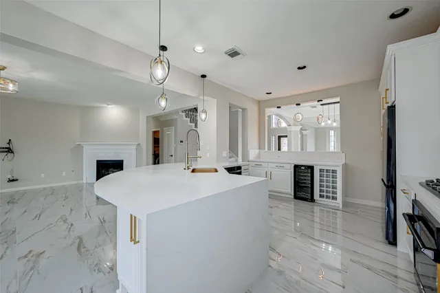 a large white kitchen with a stove a sink dishwasher a refrigerator and a fireplace with wooden floor