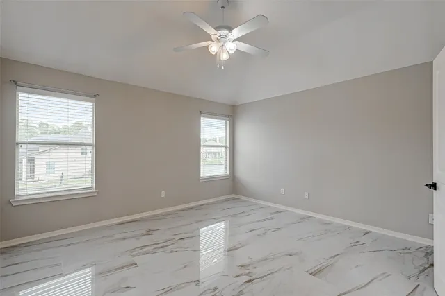a view of an empty room with window and chandelier fan