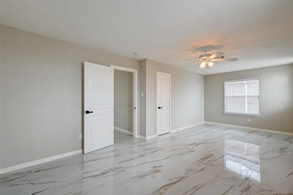 a view of an empty room with window and chandelier fan