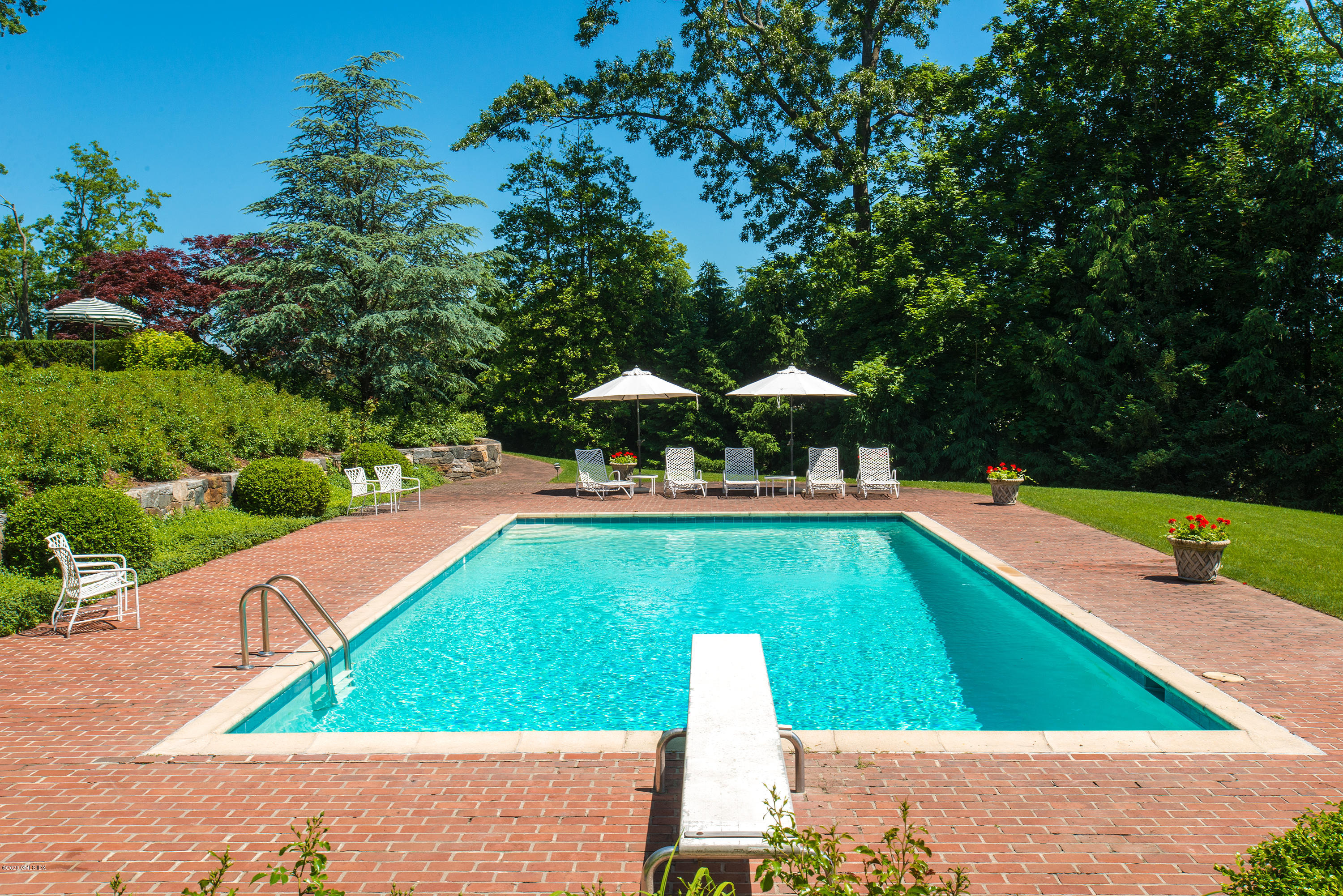 140 Field Point Circle Greenwich, CT 06830 - Photo 7 of 19 a view of a swimming pool with lawn chairs under an umbrella