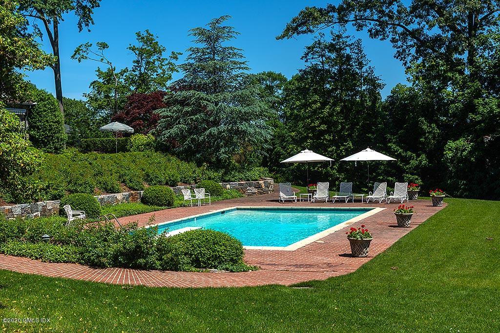 140 Field Point Circle Greenwich, CT 06830 - Photo 8 of 19 a view of a swimming pool with lawn chairs under an umbrella