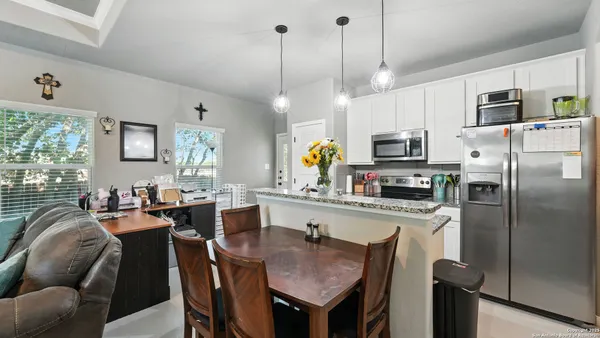 a kitchen with stainless steel appliances granite countertop a sink a stove a refrigerator cabinets and chairs