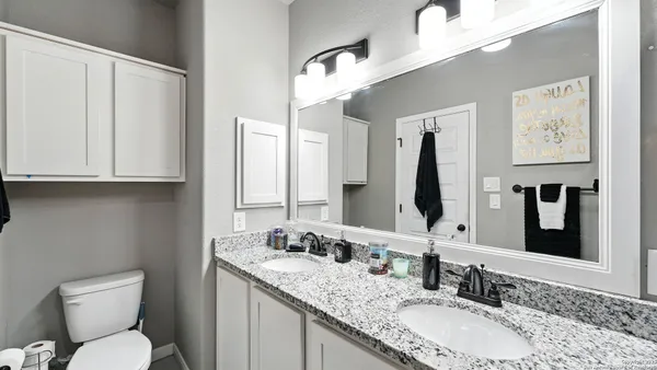 a bathroom with a granite countertop double vanity sink and a mirror