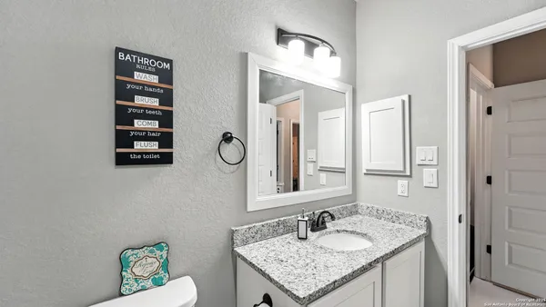 a bathroom with a granite countertop sink vanity mirror and toilet