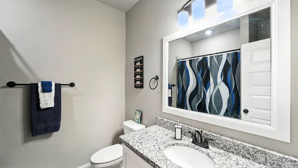 a bathroom with a granite countertop sink a toilet and shower