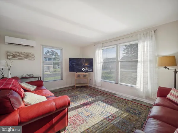a living room with furniture a flat screen tv and a window