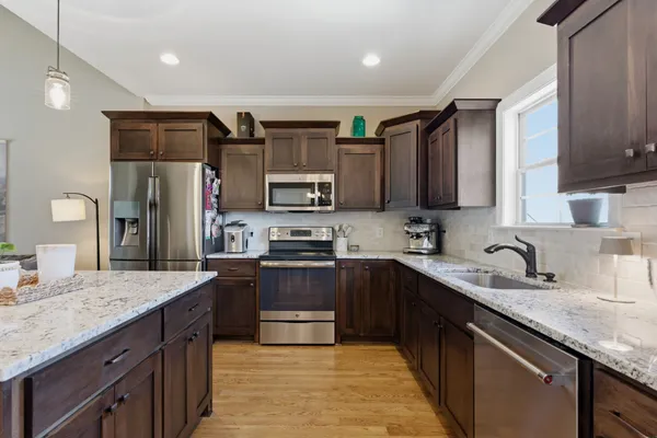 a kitchen with stainless steel appliances granite countertop a sink stove microwave and refrigerator
