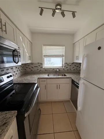 a kitchen with a refrigerator sink and cabinets