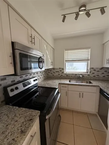 a kitchen with granite countertop a sink dishwasher stove and oven