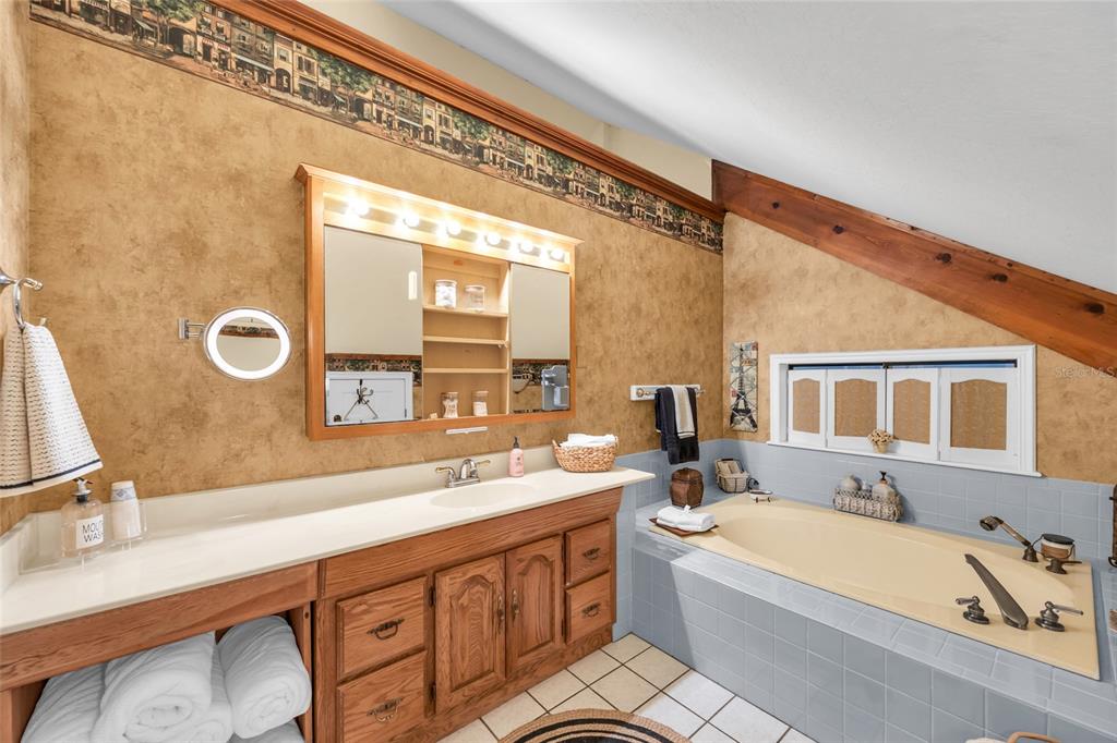 1217 Edgewood Ranch Road Orlando, FL 32835 - Photo 42 of 91 a bathroom with a double vanity sink a mirror and a bathtub
