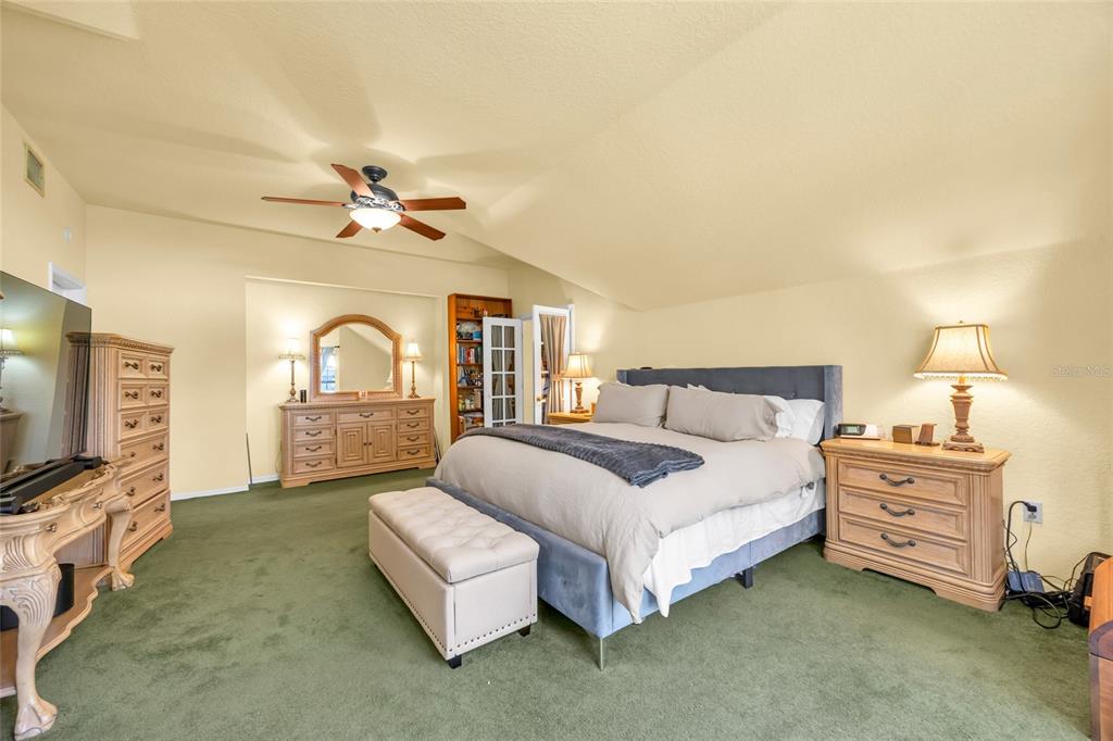1217 Edgewood Ranch Road Orlando, FL 32835 - Photo 46 of 91 a spacious bedroom with a bed a couch and a flat tv screen on dresser