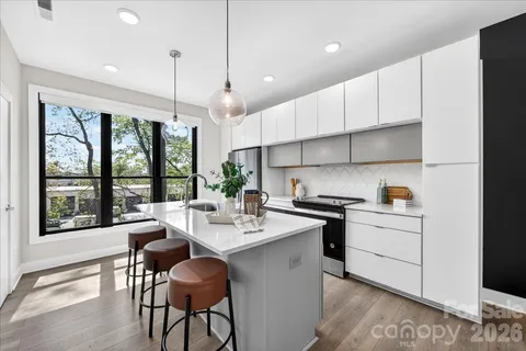 a kitchen with stainless steel appliances kitchen island a large window and cabinets