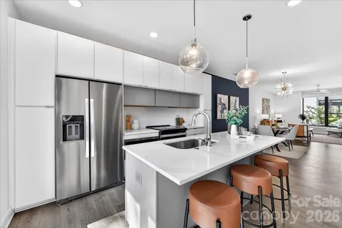 a kitchen with stainless steel appliances a dining table chairs and sink