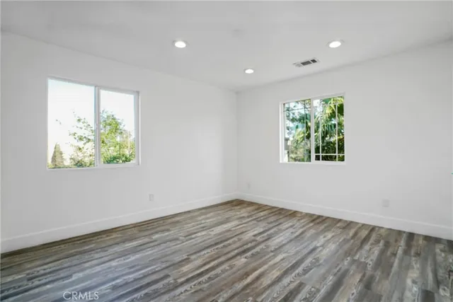 a view of an empty room with wooden floor and window