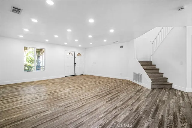 a view of an empty room with wooden floor and stairs