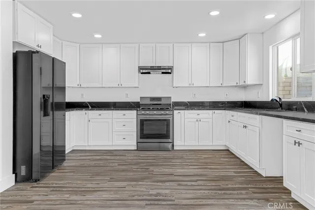 a kitchen with granite countertop white cabinets and stainless steel appliances