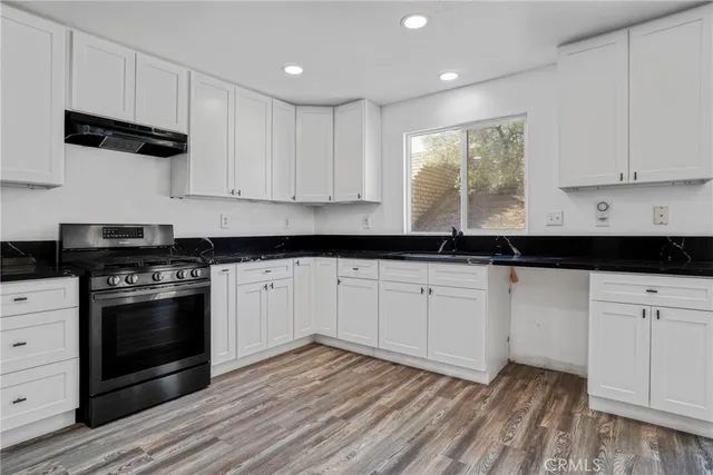 a kitchen with granite countertop white cabinets and black appliances