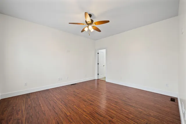 a view of a room with wooden floor ceiling fan and window