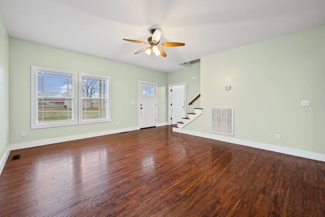 a view of empty room with wooden floor and fan
