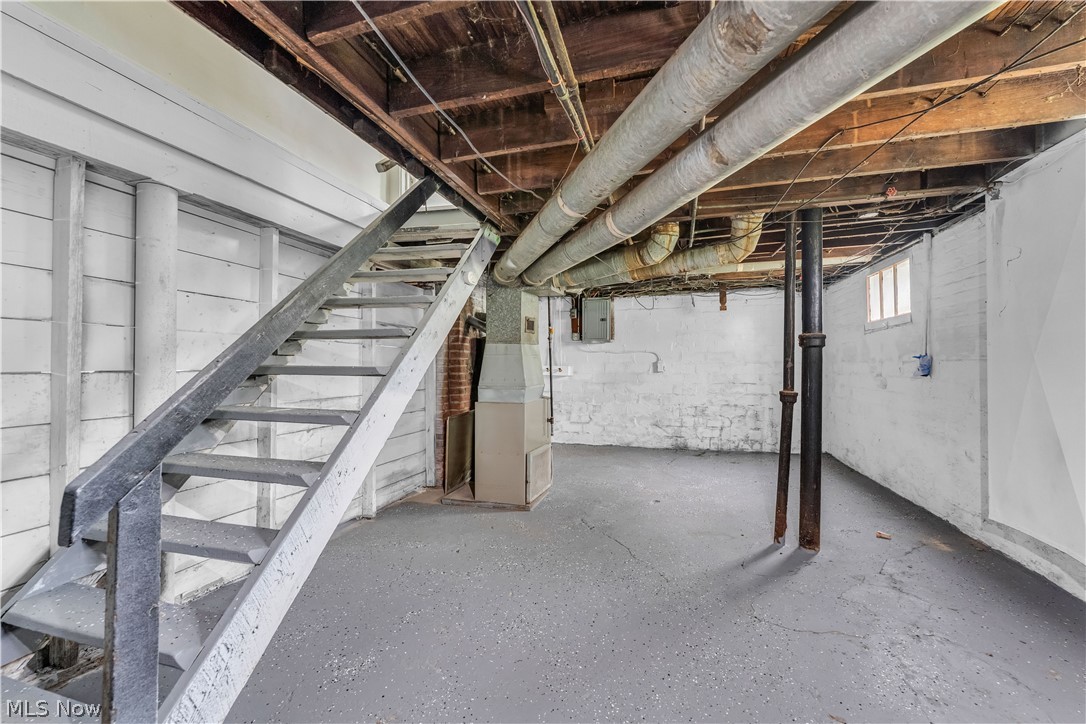 1144 East 145th Street, Unit 1/RIGHT Cleveland, OH 44110 - Photo 19 of 20 Utility space featuring painted concrete flooring, exposed ceiling joists, and a metal staircase