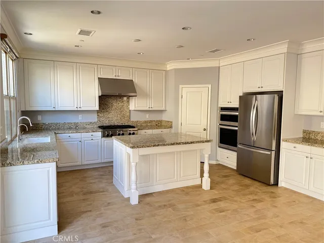 a kitchen with granite countertop a refrigerator stove top oven and sink
