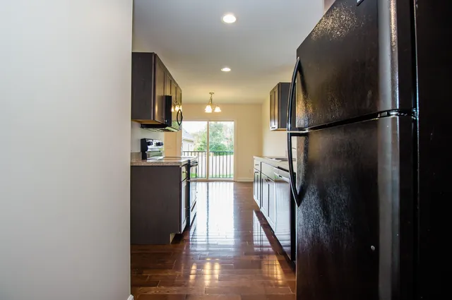 a view of a kitchen with a refrigerator and wooden floor
