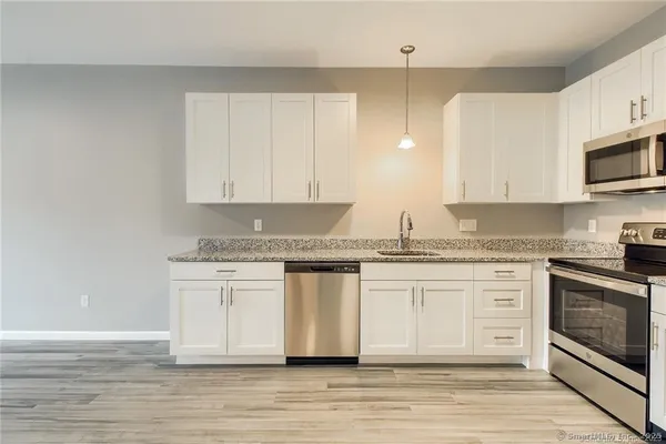 a white kitchen with granite countertop stainless steel appliances