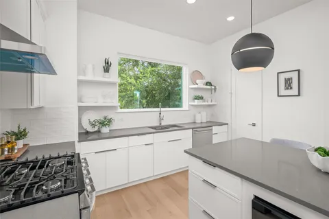 a kitchen with a sink dishwasher a stove a dining table and chairs with wooden floor