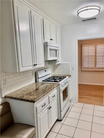 a kitchen with granite countertop white cabinets and white appliances
