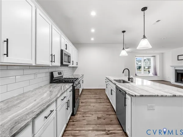 a kitchen with stainless steel appliances granite countertop a sink a stove and a wooden floors